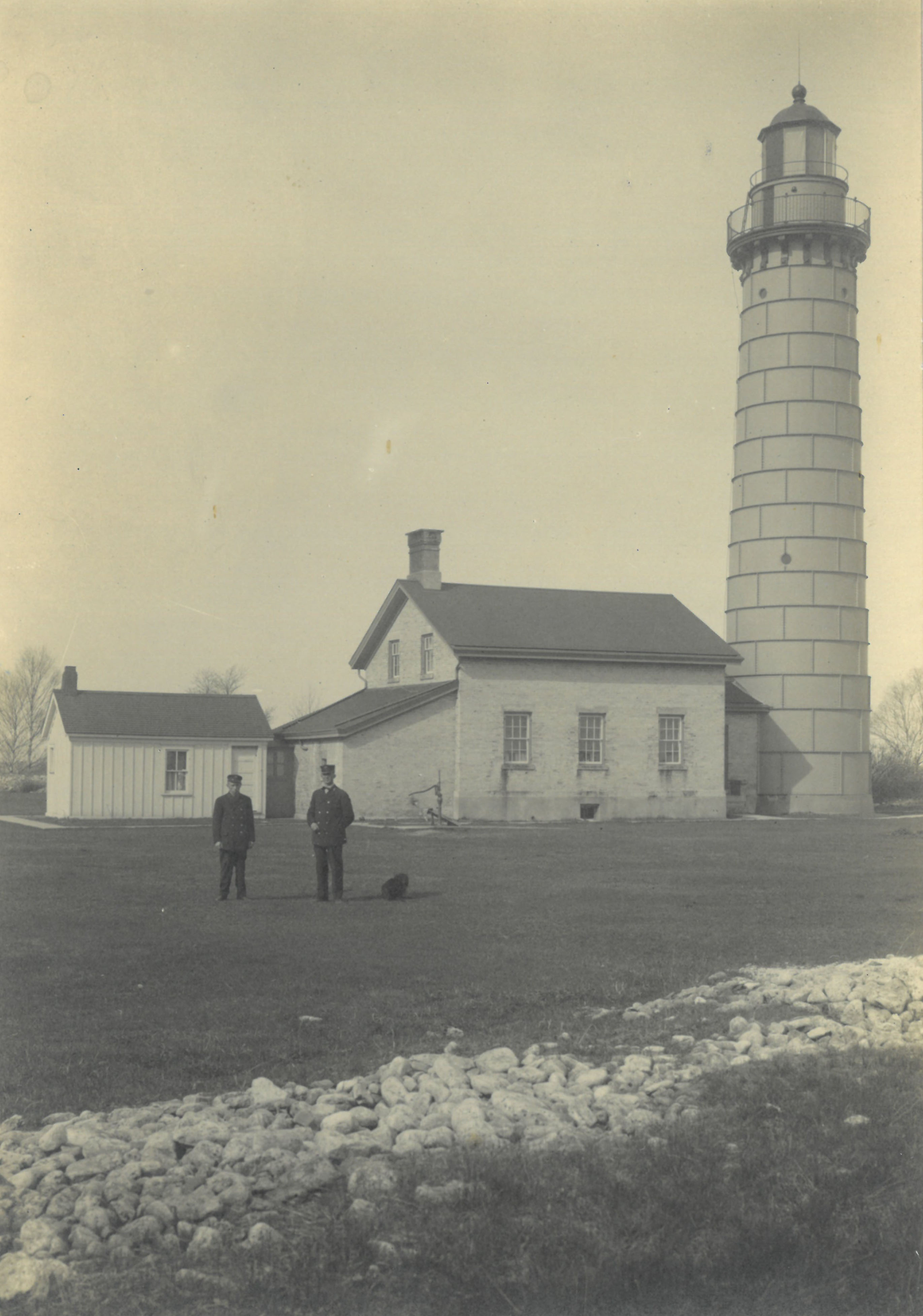 Historical photo of two uniformed men posed in front of lighthouse.